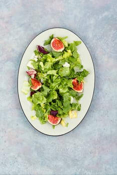 Vitamin salad of greens, ripe figs and diet cheese. Food background