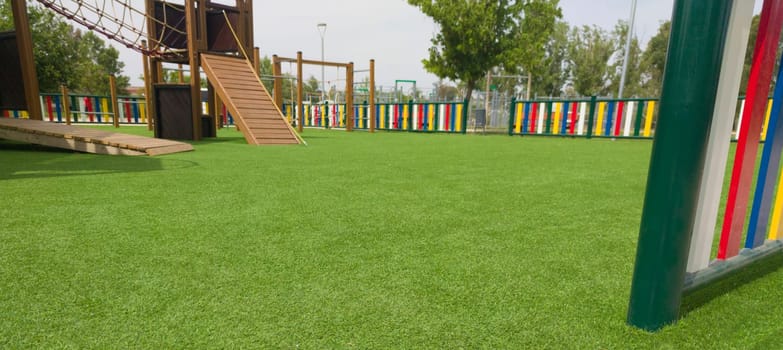 Artificial green grass floor on playground. Colourful rows of painted posts arround
