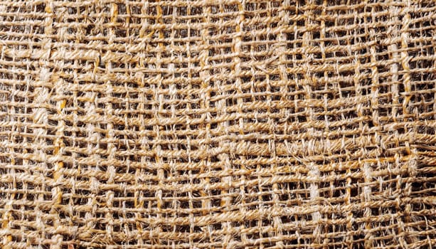 Natural textured background of intertwined threads. Macro photo of the texture of old burlap. Light brown abstract background.