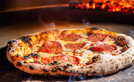 The collected pizza was put in the oven for baking. The photo shows burned wood and fire. Pizza making Process