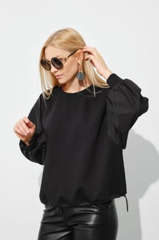 Stylish blonde woman in sunglasses touching her blonde hair