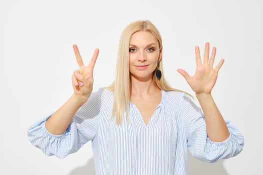 Attractive blonde woman shows seven fingers. Counting with fingers.