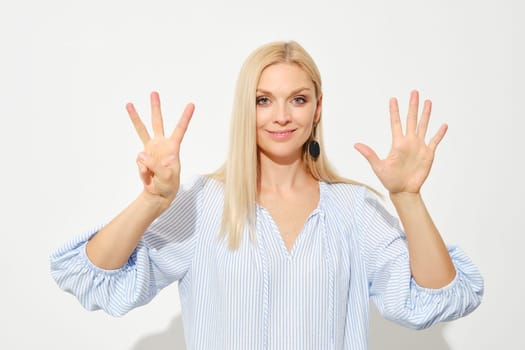 Attractive blonde woman shows eight fingers. Counting with fingers.