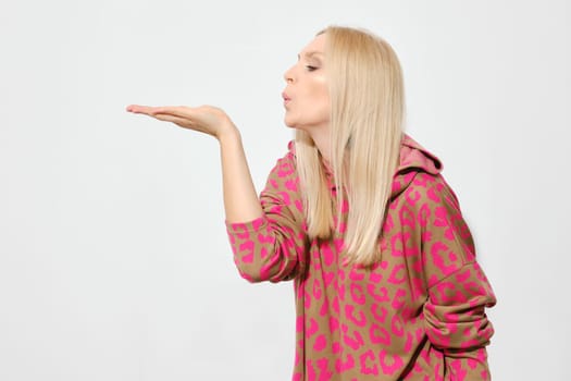 Cute woman extended her palm forward and blew on it. A woman blows a kiss.