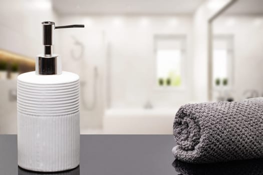 Macro of a beauty cosmetic makeup bottle and a fresh soft terry bath towel on dark table table over blurred bathroom background. Space. Beauty and Wellness concept.