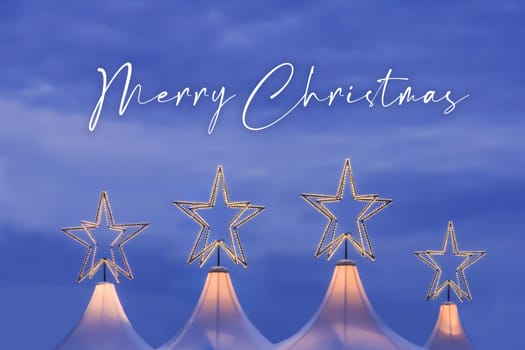 Wonderful x-mas season scene for visual or greetings card. Beautiful market tents with magic orange stars and blue sky at evening time.