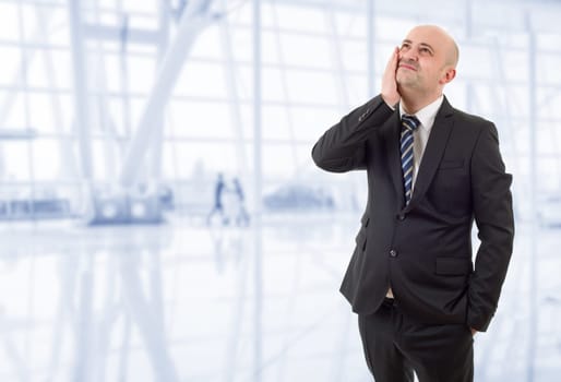 Businessman in a suit gestures with a headache, at the office