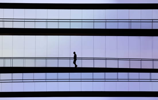 Silhouette view of young businessman in a modern office building interior with panoramic windows.