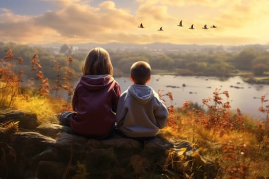 Children observing flock of geese during migration. Children sitting on hill and observing beautiful nature. Flying geese. Kids watching how flock of migrating birds. Autumn season. Autumn landscape in warm sunlight