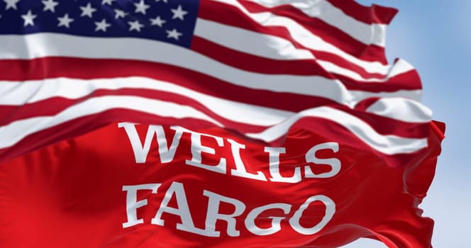 San Francisco, US, Oct. 1 2023: Close-up of Wells Fargo bank flag waving with blurred american flag in the foreground. Illustrative editorial 3d illustration. Finance and banking
