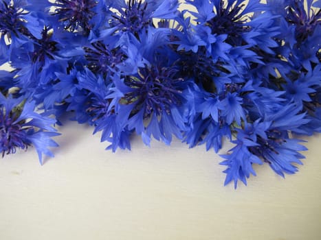Still life with blue cornflowers flowers on a wooden board