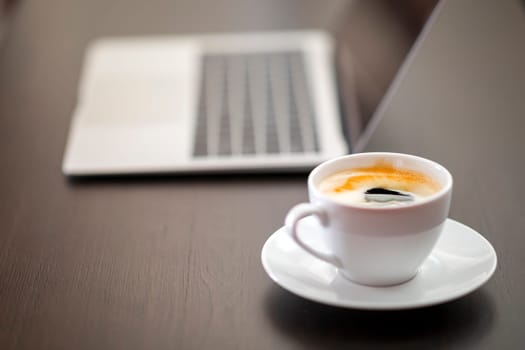 cup of coffee and laptop on wooden table
