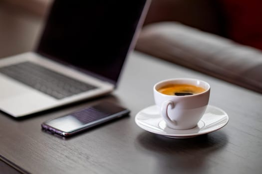 cup of coffee and laptop on wooden table