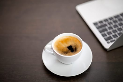 cup of coffee and laptop on wooden table