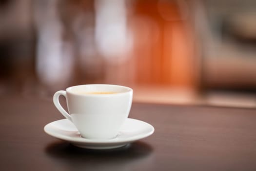 White cup of coffee on wooden table in coffee shop.