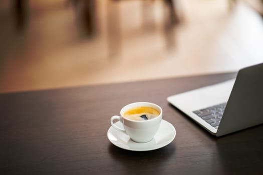cup of coffee and laptop on wooden table