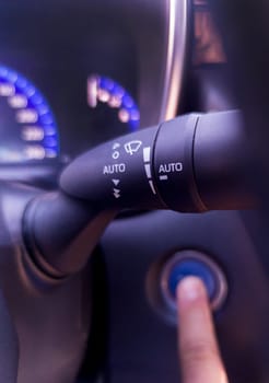 Windshield wiper lever in focus while a finger press the start button