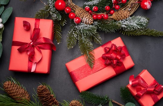 Christmas wreaths, fir branches and gifts on a black background. View from above