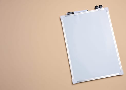 Empty white board for markers on beige background. Copy space