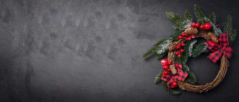 A circular Christmas wreath made of fir branches and other decorations on a black chalkboard, with space for a message