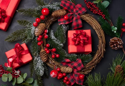 Christmas wreaths, fir branches and gifts on a black background. View from above
