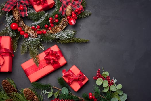 Christmas wreaths, fir branches and gifts on a black background. View from above