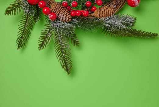 Christmas wreath made of fir branches and other decorations on a green background, copy space