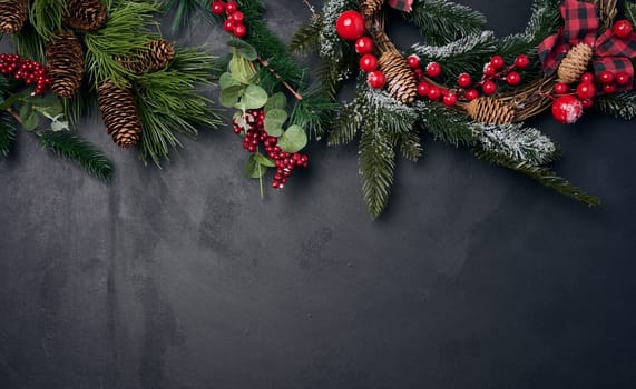 Branches and a round Christmas wreath made of fir branches and other decor on a black chalk board, space for an inscription