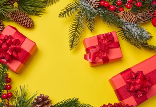 Christmas decor, gifts wrapped in red paper on a yellow background, top view. Copy space