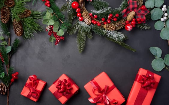 Christmas wreaths, fir branches and gifts on a black background, space for an inscription. View from above