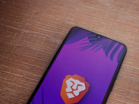 Lod, Israel - July 16,2023: Brave Private Browser app launch screen on smartphone on wooden background. Top view flat lay with copy space.