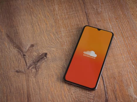 Lod, Israel - July 16,2023: SoundCloud app launch screen on smartphone on wooden background. Top view flat lay with copy space.