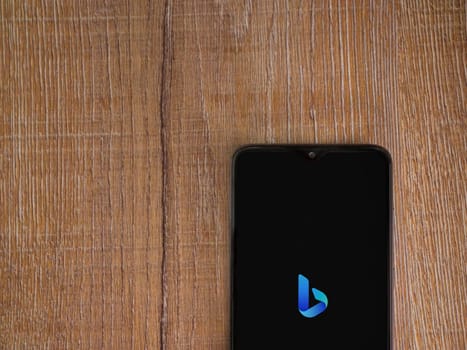 Lod, Israel - July 16,2023: Bing Browser app launch screen on smartphone on wooden background. Top view flat lay with copy space.