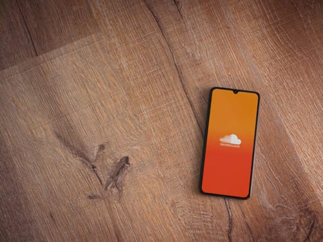 Lod, Israel - July 16,2023: SoundCloud app launch screen on smartphone on wooden background. Top view flat lay with copy space.