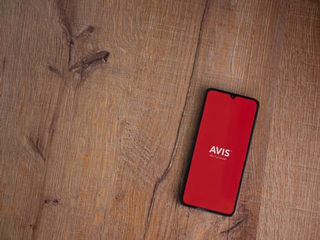 Lod, Israel - July 16,2023: Avis IL app launch screen on smartphone on wooden background. Top view flat lay with copy space.
