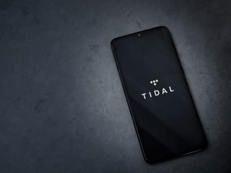 Lod, Israel - July 16,2023: TIDAL Music app launch screen on smartphone on dark marble stone background. Top view flat lay with copy space.