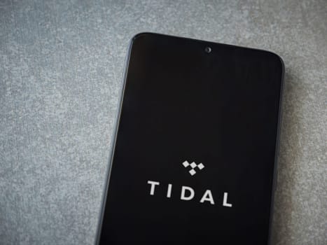 Lod, Israel - July 16,2023: TIDAL Music app launch screen on smartphone on ceramic stone background. Top view flat lay with copy space.