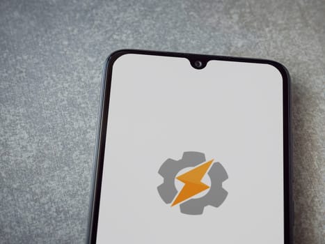 Lod, Israel - July 16,2023: Tasker app launch screen on smartphone on ceramic stone background. Top view flat lay with copy space.