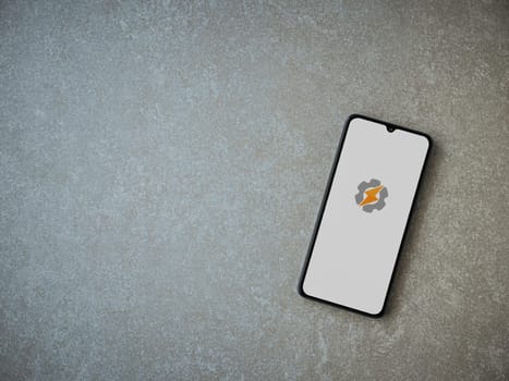 Lod, Israel - July 16,2023: Tasker app launch screen on smartphone on ceramic stone background. Top view flat lay with copy space.