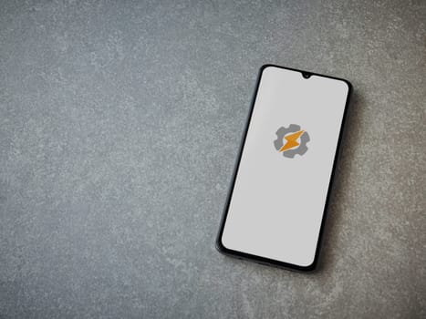 Lod, Israel - July 16,2023: Tasker app launch screen on smartphone on ceramic stone background. Top view flat lay with copy space.