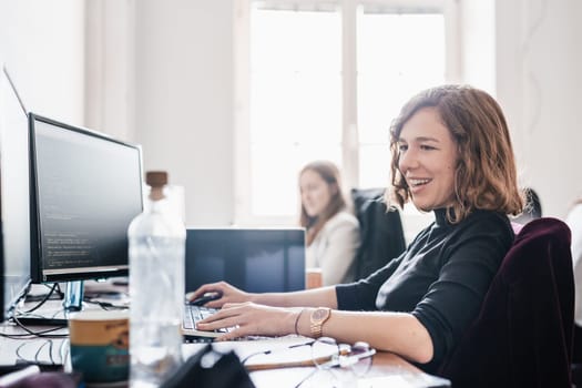 Women in startup business and entrepreneurship. Yound devoted female AI programmers and IT software developers team programming on desktop computer in startup company share office space.