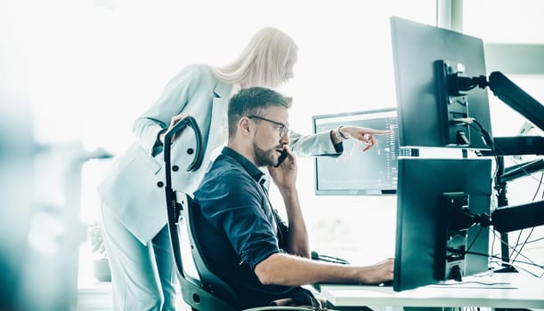 Stock broker business team trading online watching charts and data analyses on multiple computer screens in modern corporate work station office.