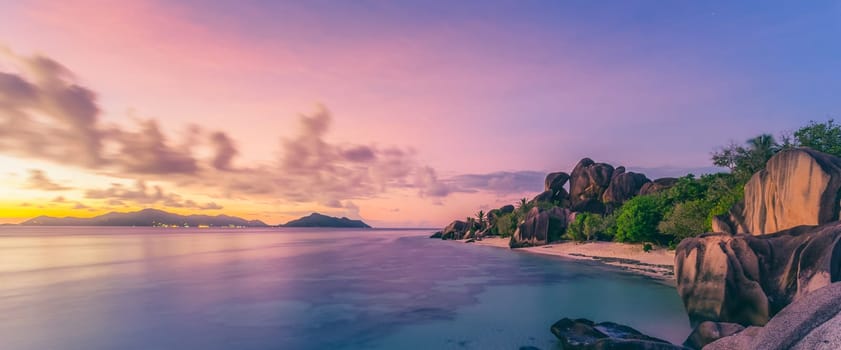 Beautifully shaped granite boulders and a dramatic sunset at picture perfect tropical Anse Source d'Argent beach, La Digue island, Seychelles.