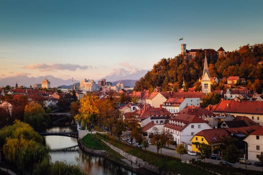 Cityscape of the Slovenian capital Ljubljana at sunset. Ljubljana castle on hill above town. River Ljubljanica running trough city center. Karavanke mountains in background.
