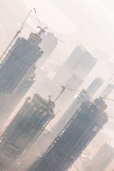 Huge skyscrappers construction site with cranes on top of buildings. Rapid urban and construction sector development or inflation of real estate bubble.