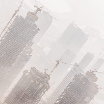 Huge skyscrappers construction site with cranes on top of buildings. Rapid urban and construction sector development or inflation of real estate bubble.