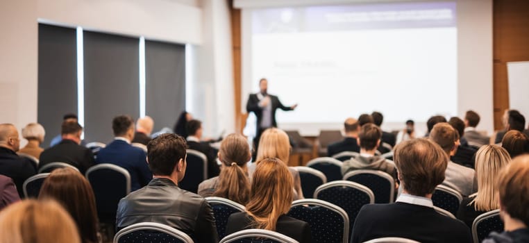 Speaker giving a talk in conference hall at business event. Rear view of unrecognizable people in audience at the conference hall. Business and entrepreneurship concept