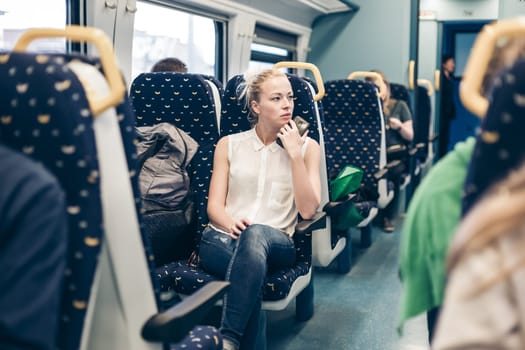 Young woman looking trough window while traveling by train.
