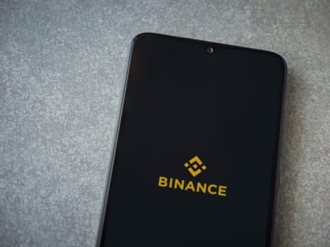 Lod, Israel - July 16,2023: Binance app launch screen on smartphone on ceramic stone background. Top view flat lay with copy space.