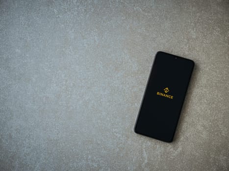 Lod, Israel - July 16,2023: Binance app launch screen on smartphone on ceramic stone background. Top view flat lay with copy space.